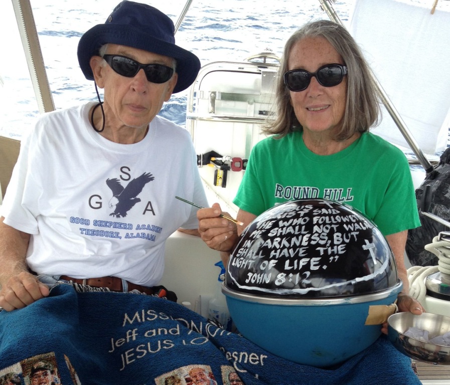 38. Before deploying the NOAA drifter buoy, Jeff and Anne posed with the buoy, with the Bible verse John 8-12 painted on the top surface, and the Mission Joyful blanket given to them by the congregation of the Huntsville First United Methodist Chapel.