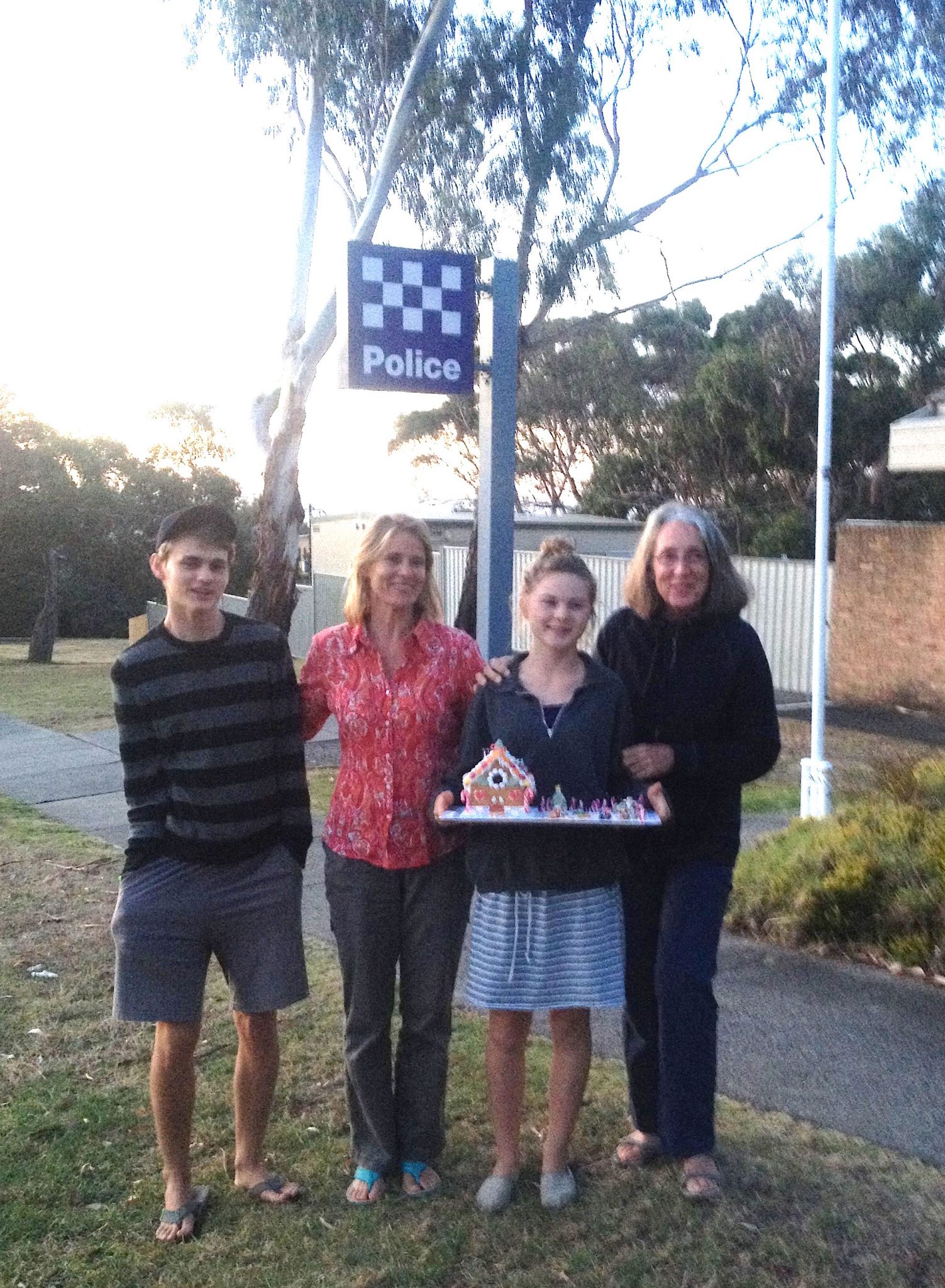 131. Gabrielle, Beatrice, Josh and I stand in front of the police department on Phillip Island. Gabrielle chose to give the gingerbread house she made to the policemen for Christmas
